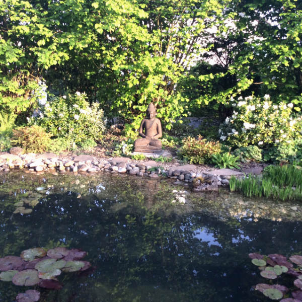 Buddhafigur sitzend am Teich